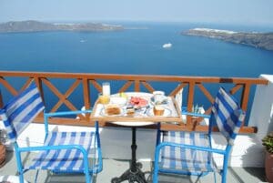 A table with a tray of food and blue chairs by the sea