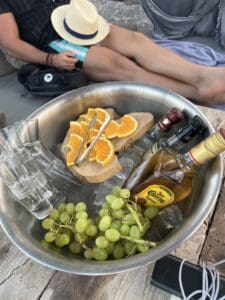 A bowl with alcohol, grapes, orange slices, and ice